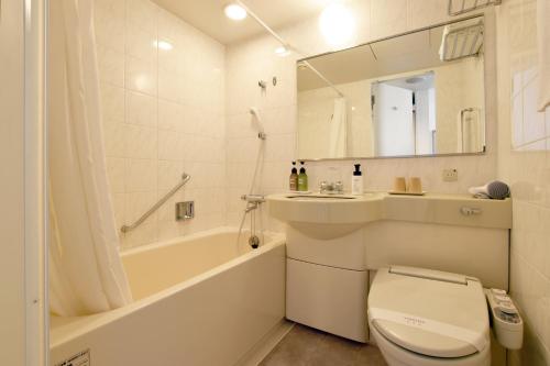 a bathroom with a toilet and a tub and a sink at Hotel Sapporo Sun Plaza in Sapporo