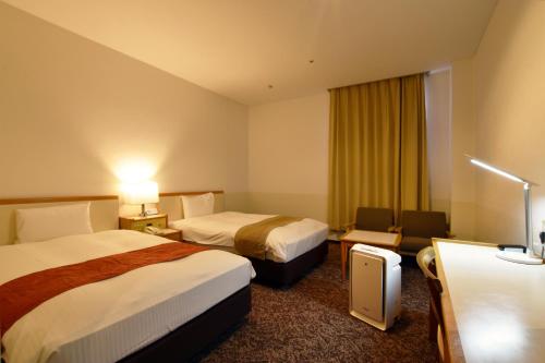 a hotel room with two beds and a couch at Hotel Sapporo Sun Plaza in Sapporo