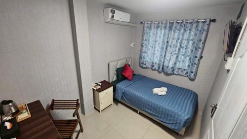 a small bedroom with a blue bed and a desk at แกร็บสลีปโฮสเทล แอร์พอร์ตดอนเมือง in Ban Ko