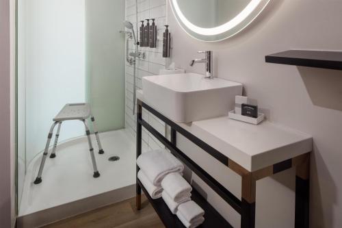 a bathroom with a white sink and a mirror at The Clara Hotel Plano, Tapestry Collection by Hilton in Plano