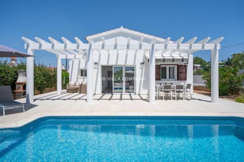 a villa with a swimming pool and a pergola at Villa de Amigos in Cala en Porter
