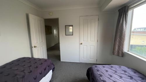 a bedroom with a purple bed and a window at Beachside Bliss in Tauranga