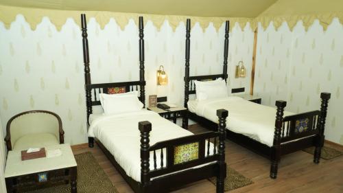 a room with two beds and a table with a chair at Evoke Rambagh Resort Ayodhya in Ayodhya
