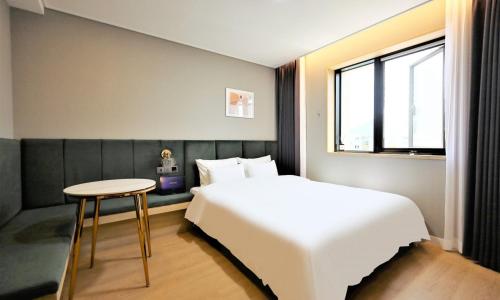 a bedroom with a bed and a table and a window at De Lamour Hotel in Tongyeong