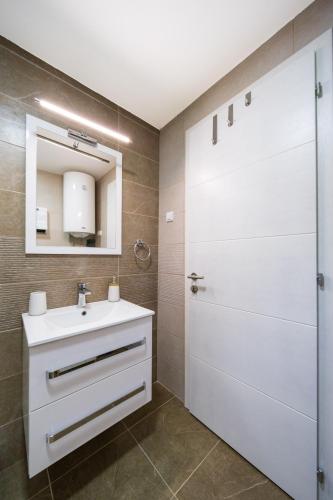 a bathroom with a white sink and a door at Dream Apartment in Vrnjačka Banja