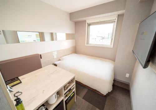 a small room with a bed and a desk at Super Hotel Premier Obihiro Ekimae in Obihiro