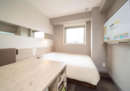 a small room with a bed and a desk at Super Hotel Premier Obihiro Ekimae in Obihiro