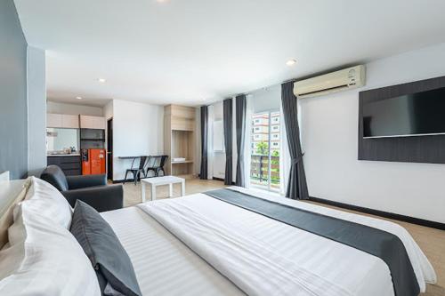 a hotel room with a large bed and a television at Le Nara Residence in Jomtien Beach