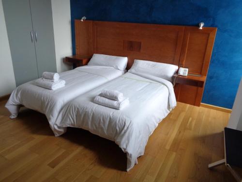 a bedroom with a large bed with white sheets and towels at Hotel Villa De Betanzos in Betanzos