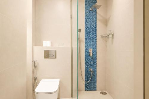 a bathroom with a toilet and a glass shower at Avyanna Gulhi Beach Hotel in Gulhi