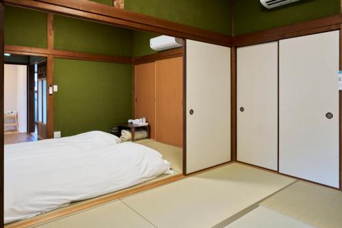 a bedroom with green walls and a bed with white sheets at SEN HAVEN Sakurai in Shingū