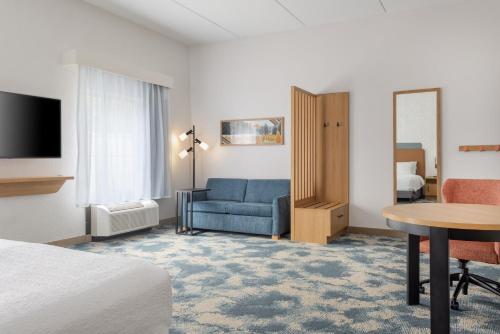 a hotel room with a bed and a table and a couch at Hampton Inn & Suites Berkshires-Lenox in Lenox