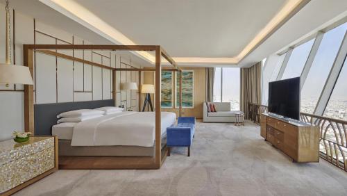a bedroom with a bed and a television and a balcony at Hyatt Regency Riyadh Olaya in Riyadh