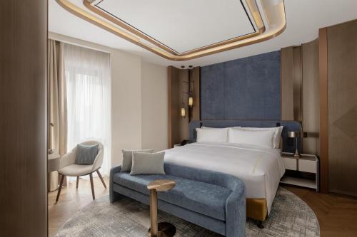 a hotel room with a bed and a blue couch at Doubletree By Hilton Tashkent in Tashkent