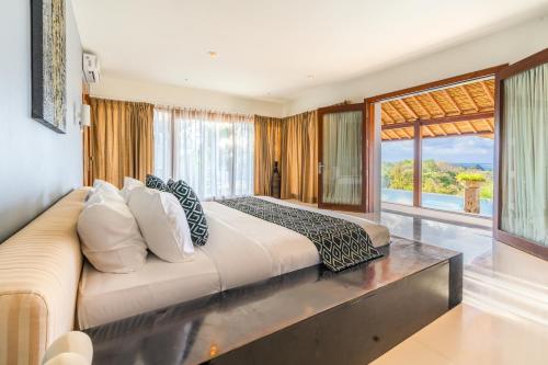 a bedroom with a large bed and a large window at Hening Jimbaran in Jimbaran