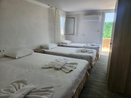 a hotel room with three beds and a window at Çeşme MASAL in Çeşme