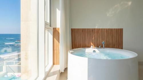 a bath tub in a room with a large window at Donghae Badadam Ocean View Spa Pension in Donghae