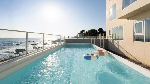 a swimming pool on top of a building next to the ocean at Donghae Badadam Ocean View Spa Pension in Donghae