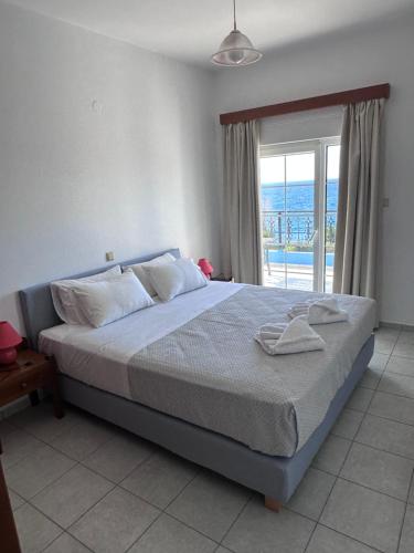 a bedroom with a bed with a view of the ocean at Cypriana Apartments in Makry Gialos