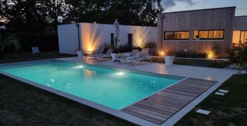 a swimming pool in front of a house at night at Entre Mer & Filles in Sainte-Soulle