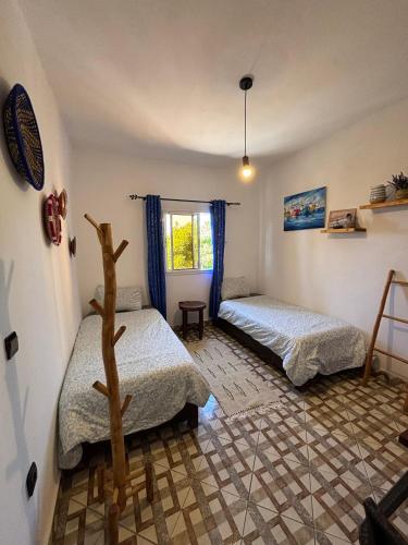 a room with two beds and a window at Jara Cimrmann surf house in Imsouane