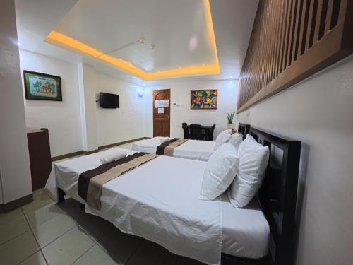 a hotel room with two beds and a television at White Beach Resort Bar & Restaurant in Puerto Galera