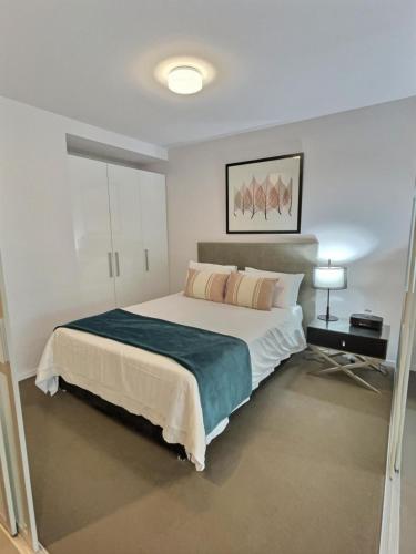 a bedroom with a large bed with a blue blanket at Modern 1BR Views in Belconnen in Belconnen