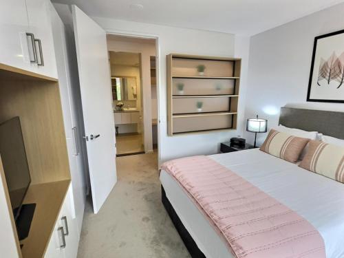 a bedroom with a large bed with a pink blanket at Balcony Apt with 1 Bedroom in Belconnen