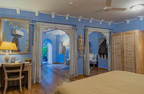 a bedroom with blue walls and a table and a desk at Ajit Bhawan - A Palace Resort in Jodhpur
