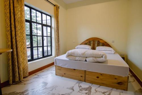 a bedroom with a bed and a large window at pumzika hill in Arusha