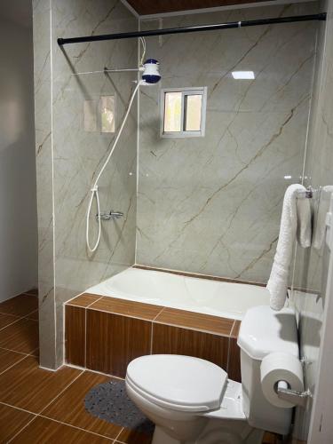 a bathroom with a tub and a toilet and a shower at Hotel Atlántida in La Ceiba