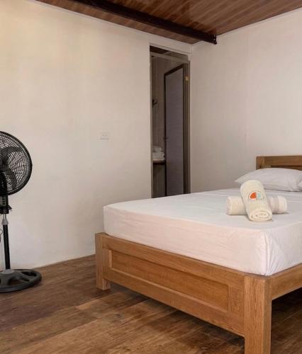 a bedroom with a bed with white sheets and a fan at ECOHOTEL LILI in Puerto Limón