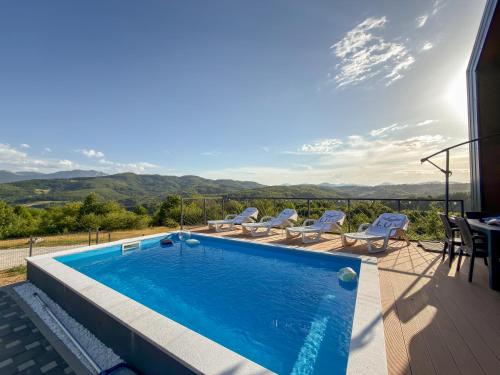 a swimming pool with chairs and a view of the mountains at Lux House in Hadžići