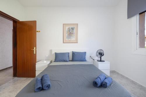 a bedroom with a bed with blue slippers on it at Villa Sueños Piscina Costa Dorada in Calafell