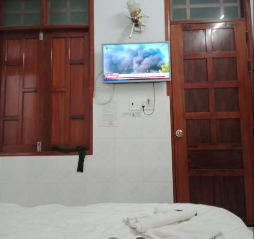 a bedroom with a tv on the wall and a bed at Nhà Nghỉ Motel NGỌC KIM NGÂN in Quy Nhon