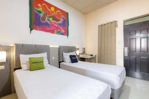 a hotel room with two beds and a door at Urbanview Hotel Delima 101 Syariah in Serang