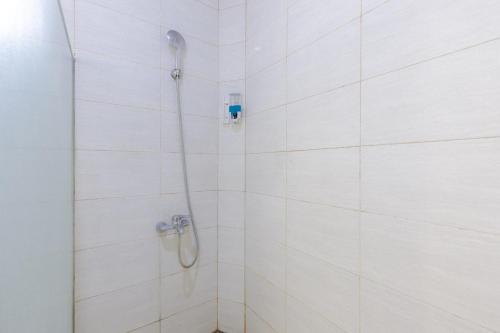 a shower with a shower head in a white tiled bathroom at Urbanview Hotel Delima 101 Syariah in Serang