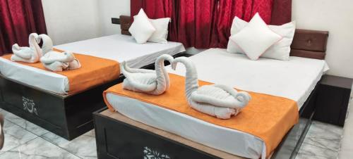 three beds with swans on them in a room at Hotel Royal Orbit in Rajauli