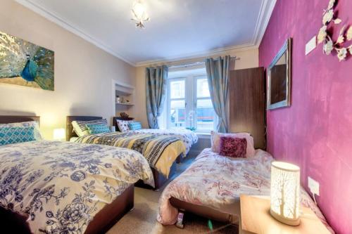 a bedroom with three beds and a pink wall at Edinburgh Central Drumdryan ApartHotel in Edinburgh