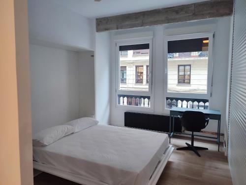 a bedroom with a bed and a desk and two windows at MBE Bilbao Centro, 3Hab, 2 Baños, jacuzzi in Bilbao