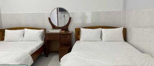 a bedroom with two beds with a mirror at Nhà Nghỉ Motel NGỌC KIM NGÂN in Quy Nhon