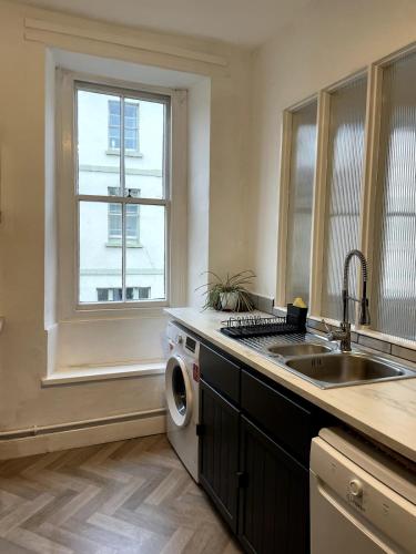 a kitchen with a sink and a washing machine at 2 Bed Period Flat with parking in Ross on Wye