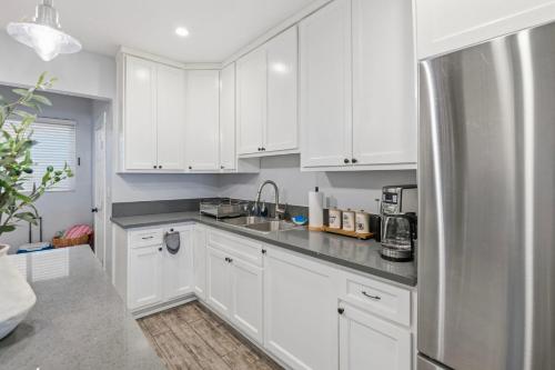 a kitchen with white cabinets and a stainless steel refrigerator at Casa Playa Long Beach in Long Beach