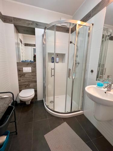 a bathroom with a shower and a toilet and a sink at Maritime Apartment in Świnoujście