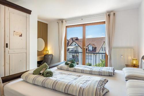 two beds in a room with a large window at bleib. Boutique Fewos Bodensee in Radolfzell am Bodensee