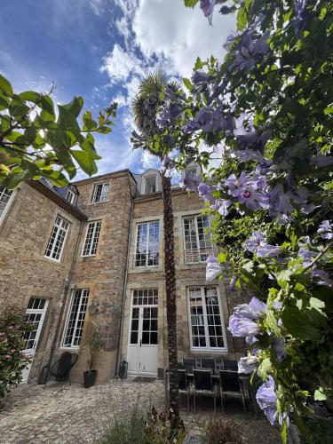 an old stone building with windows and purple flowers at Maison Saint Christophe in Le Mans