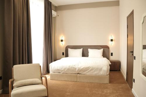 a bedroom with a white bed and a chair at Monteva Boutique Hotel in Almaty