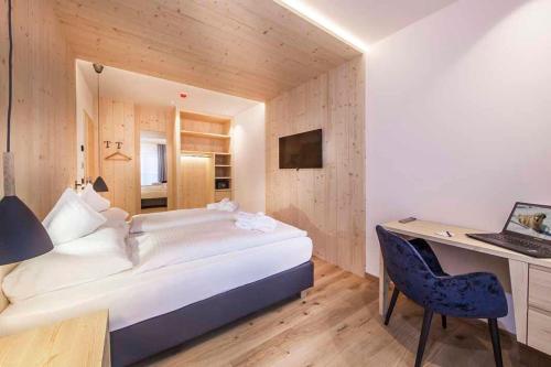 a bedroom with a bed and a desk and a computer at Hotel Garni Broi - Charme & Relax in Selva di Val Gardena