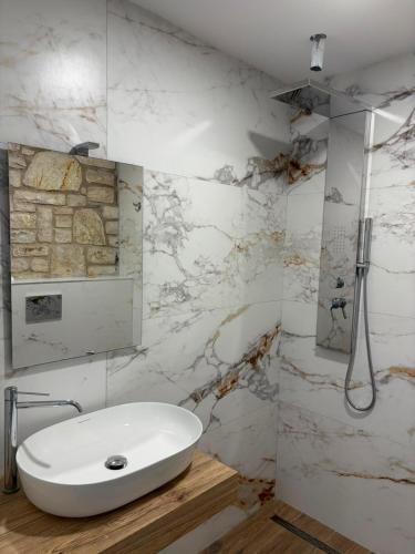 a white bathroom with a sink and a shower at Monarch Beach in Borsh