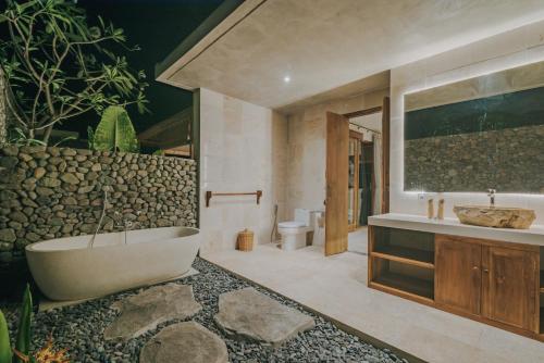 a bathroom with a tub and a toilet and a sink at Villa Danginan & Dajanan Pemuteran in Pemuteran